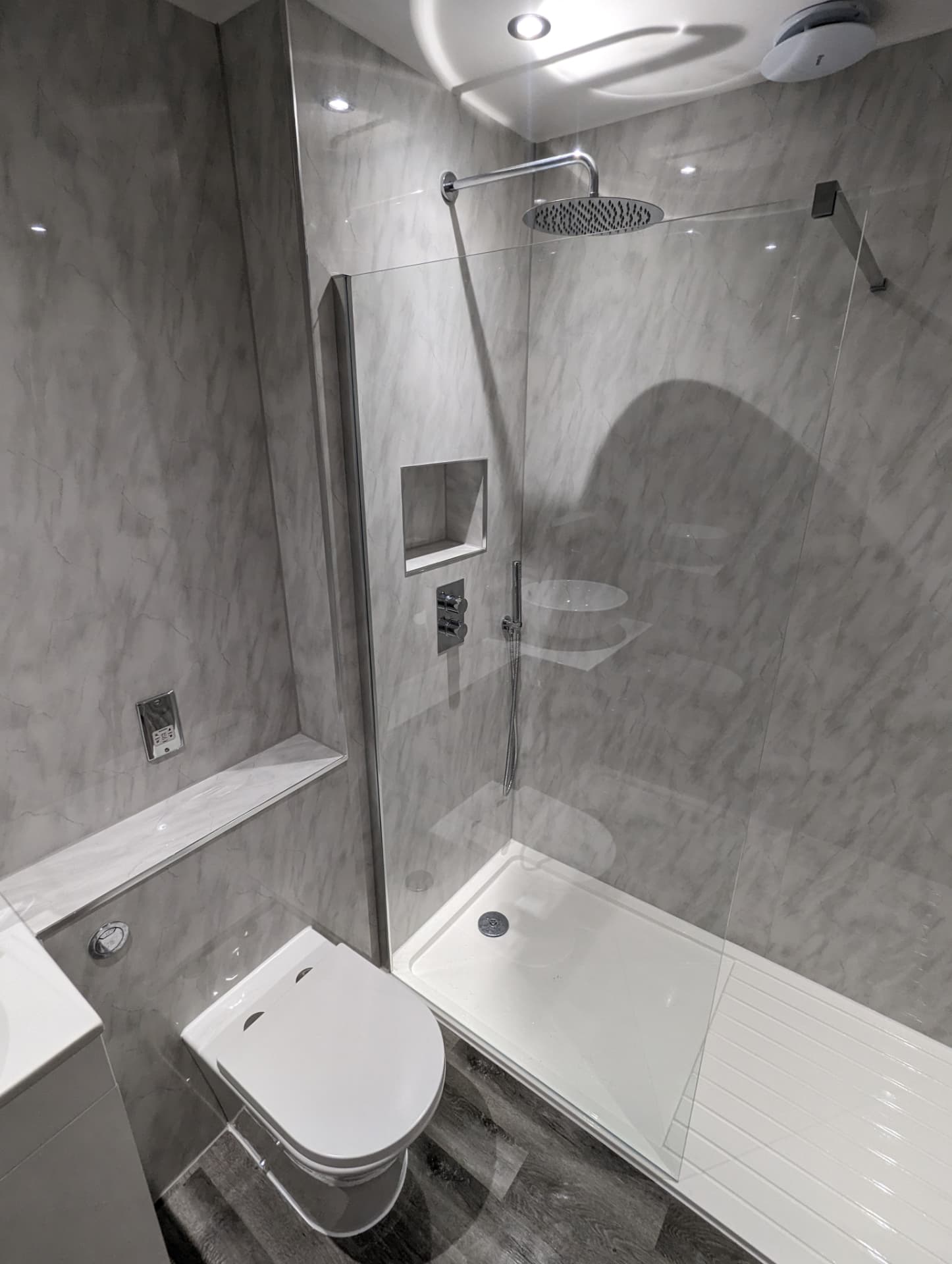 Grey marble effect bathroom with chrome rainfall shower, recessed niche and walk-in tray